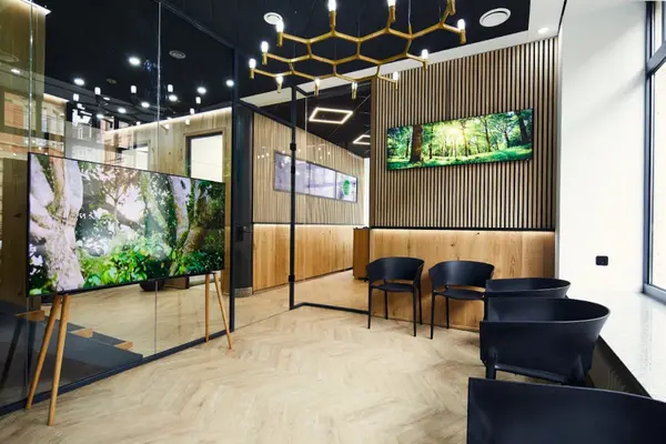 Modernes Wartezimmer mit Holzdekor, Glaswänden, schwarzen Stühlen und Naturbildern.